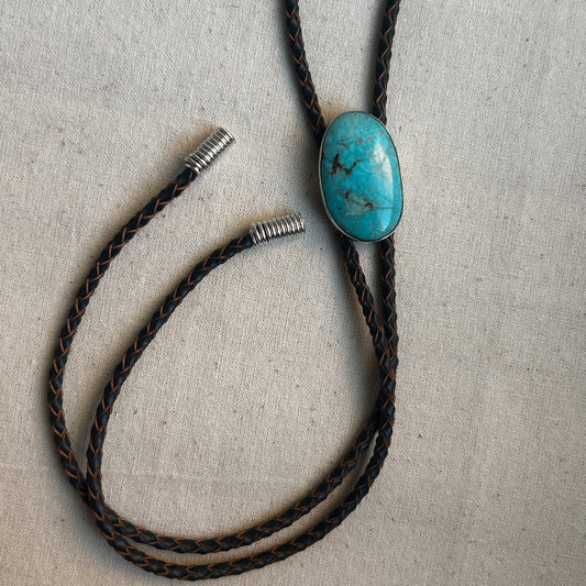 Turquoise bolo tie showing leather cord ans handmade silver tips.