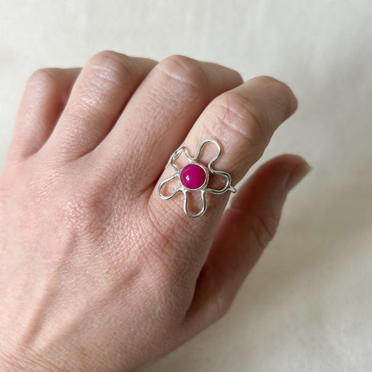 Silver flower shaped ring with pink stone with a grey background 