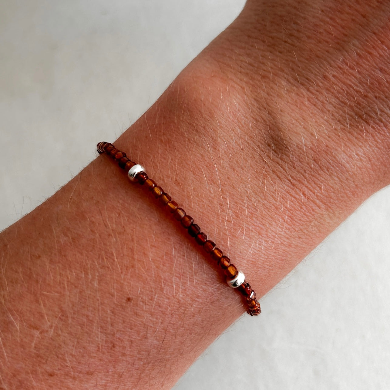 Brown beaded bracelet on a wrist against a white background