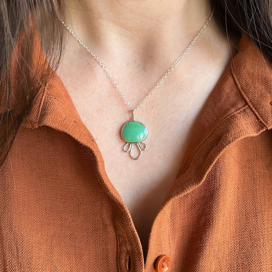 Green turquiose pendant with petal-like border worn by model