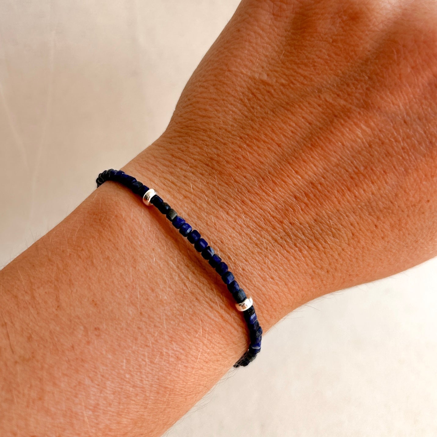 Navy blue beaded bracelet on a wrist with a neutral background
