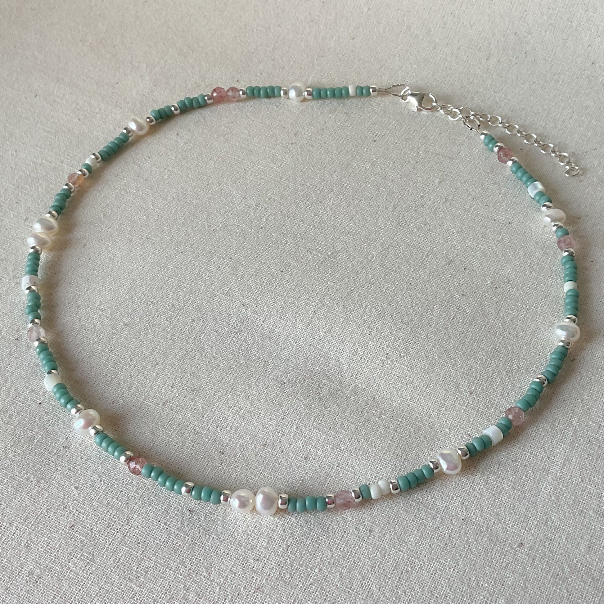 Beaded necklace with turquoise and white beads on a light gray background