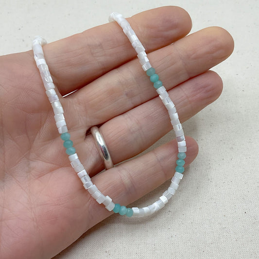 Hand wearing a delicate beaded bracelet on a light background