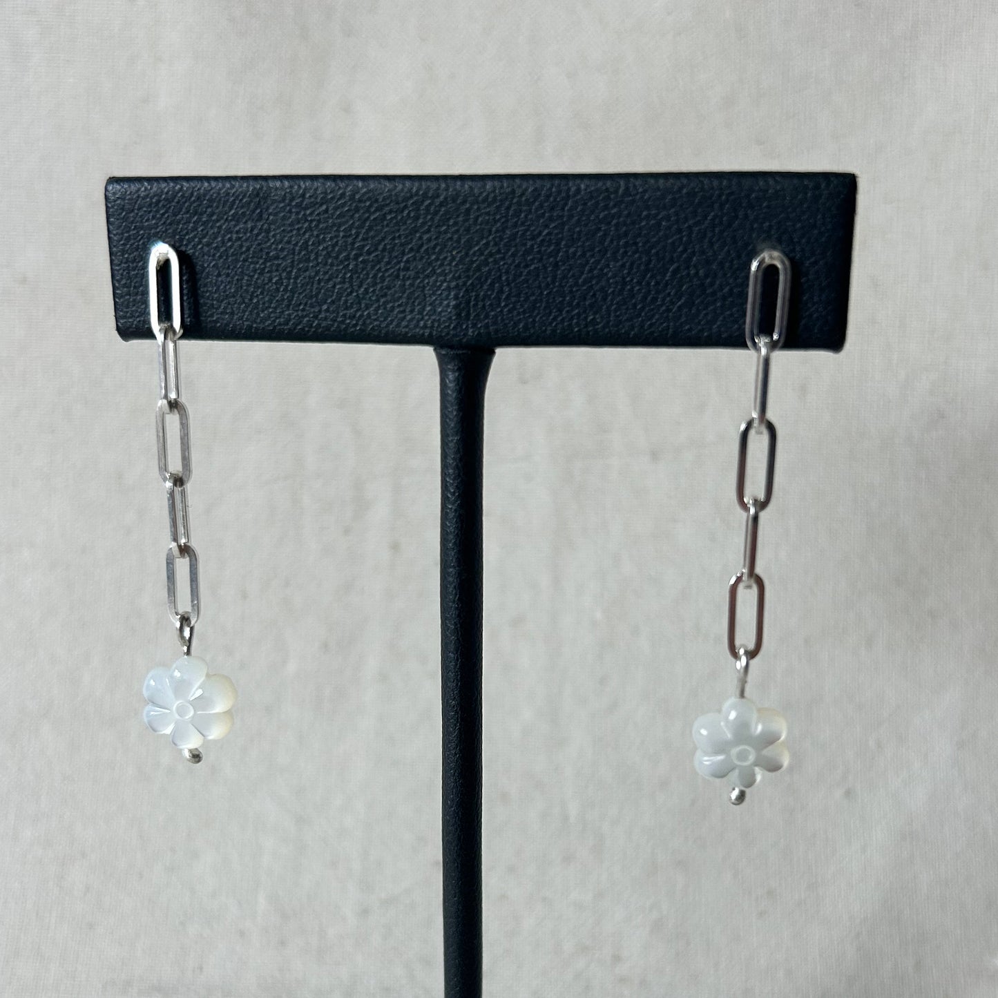 Black stand with chain earrings on gray background 