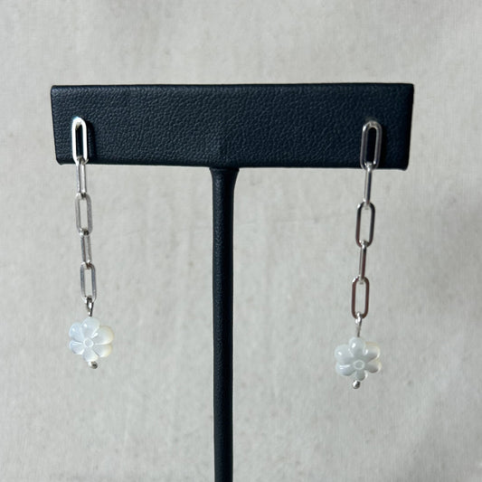 Black stand with chain earrings on gray background 