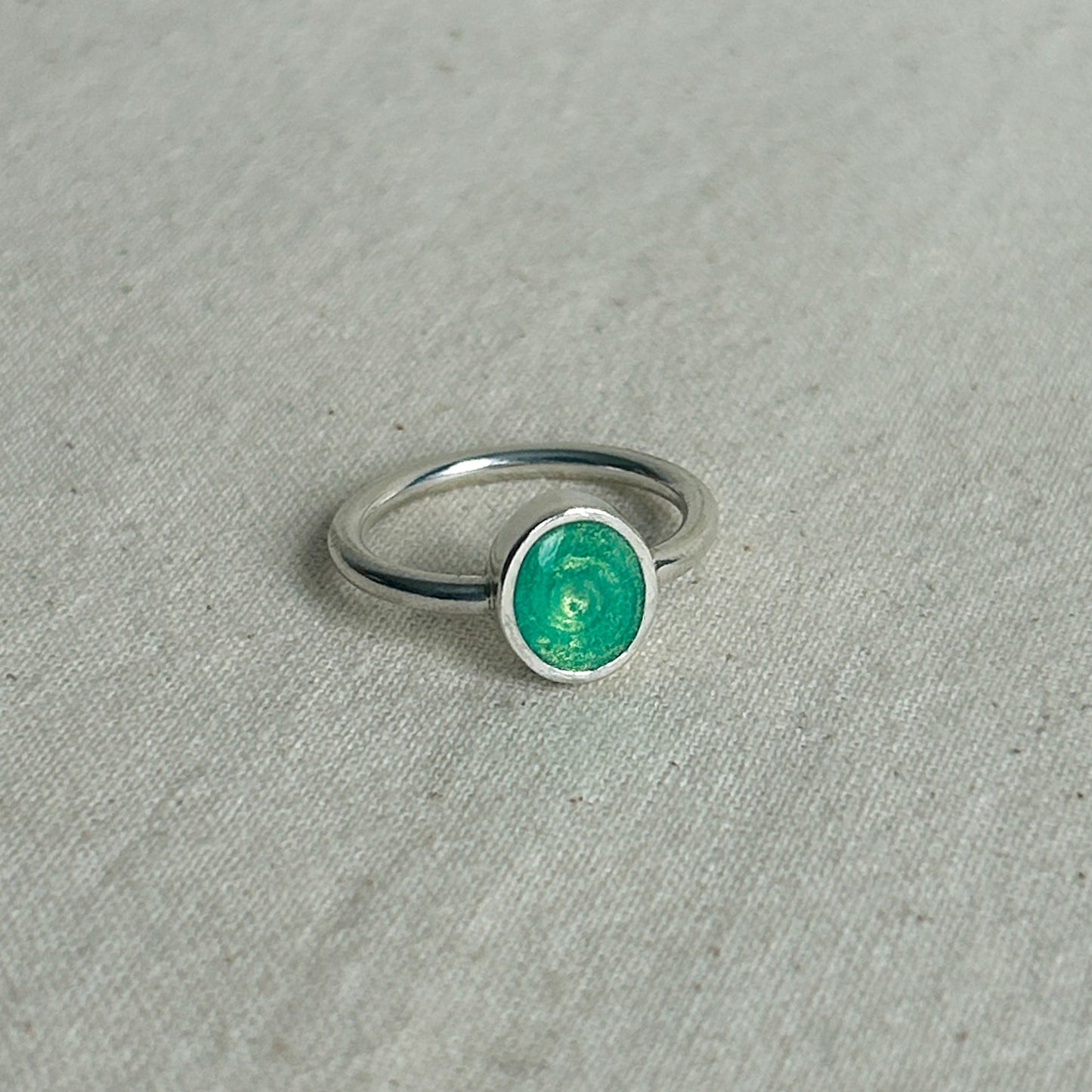 Silver ring with a green stone on a gray fabric background
