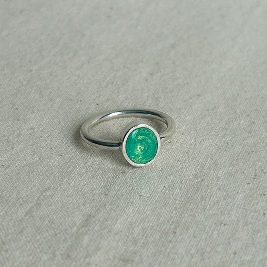 Silver ring with a green stone on a gray fabric background