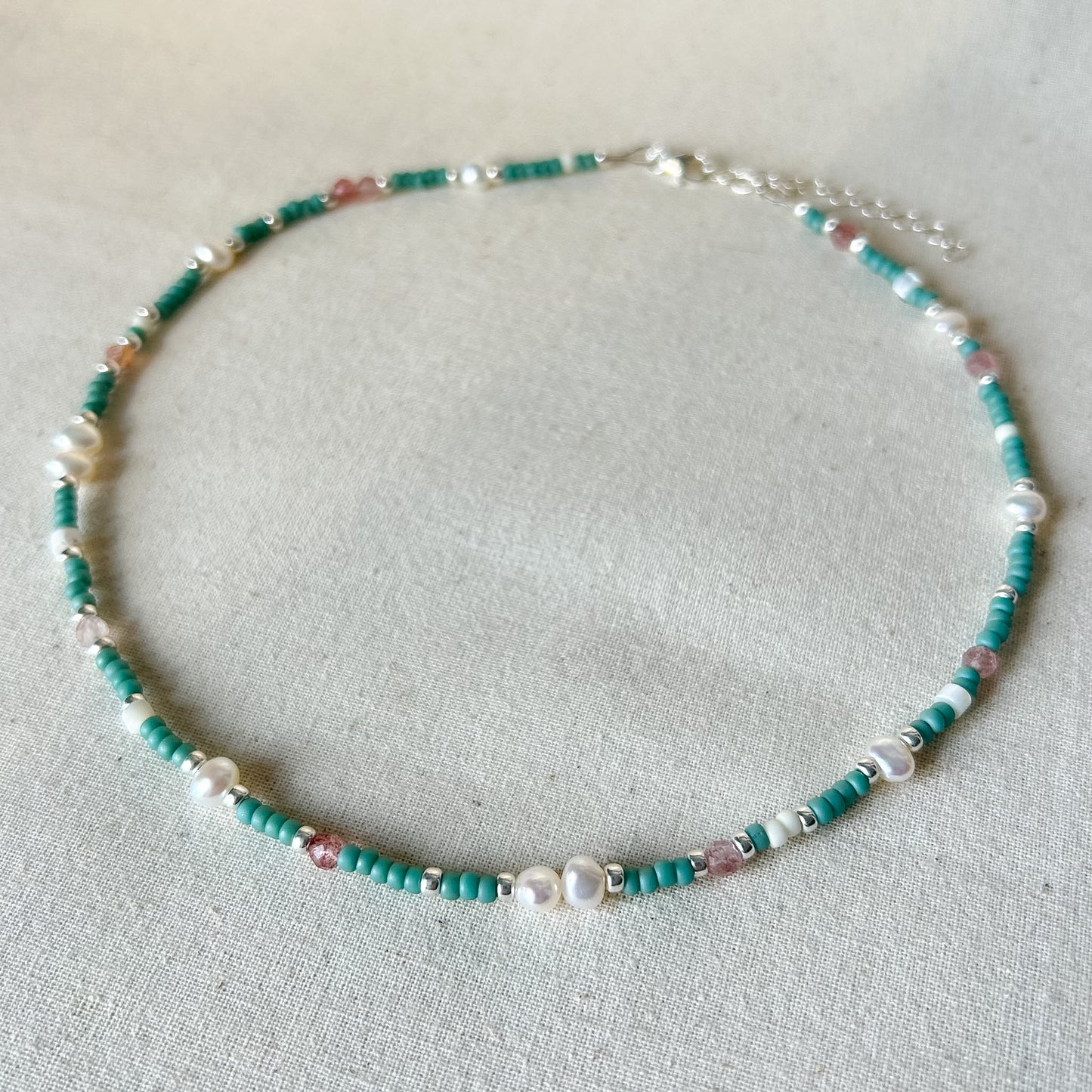 Necklace with green and white beads on a light gray background