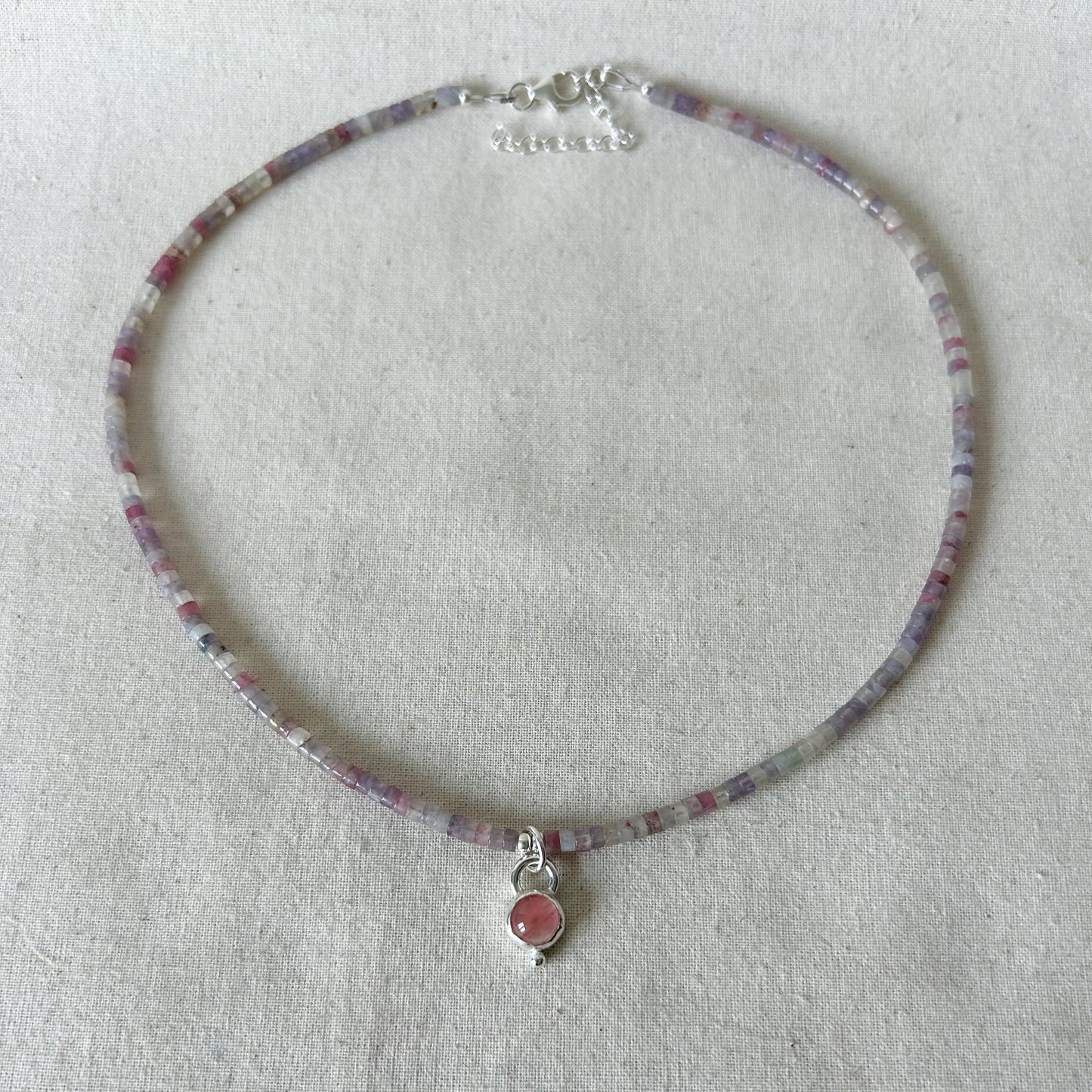 Pink necklace with pendant on light gray background 