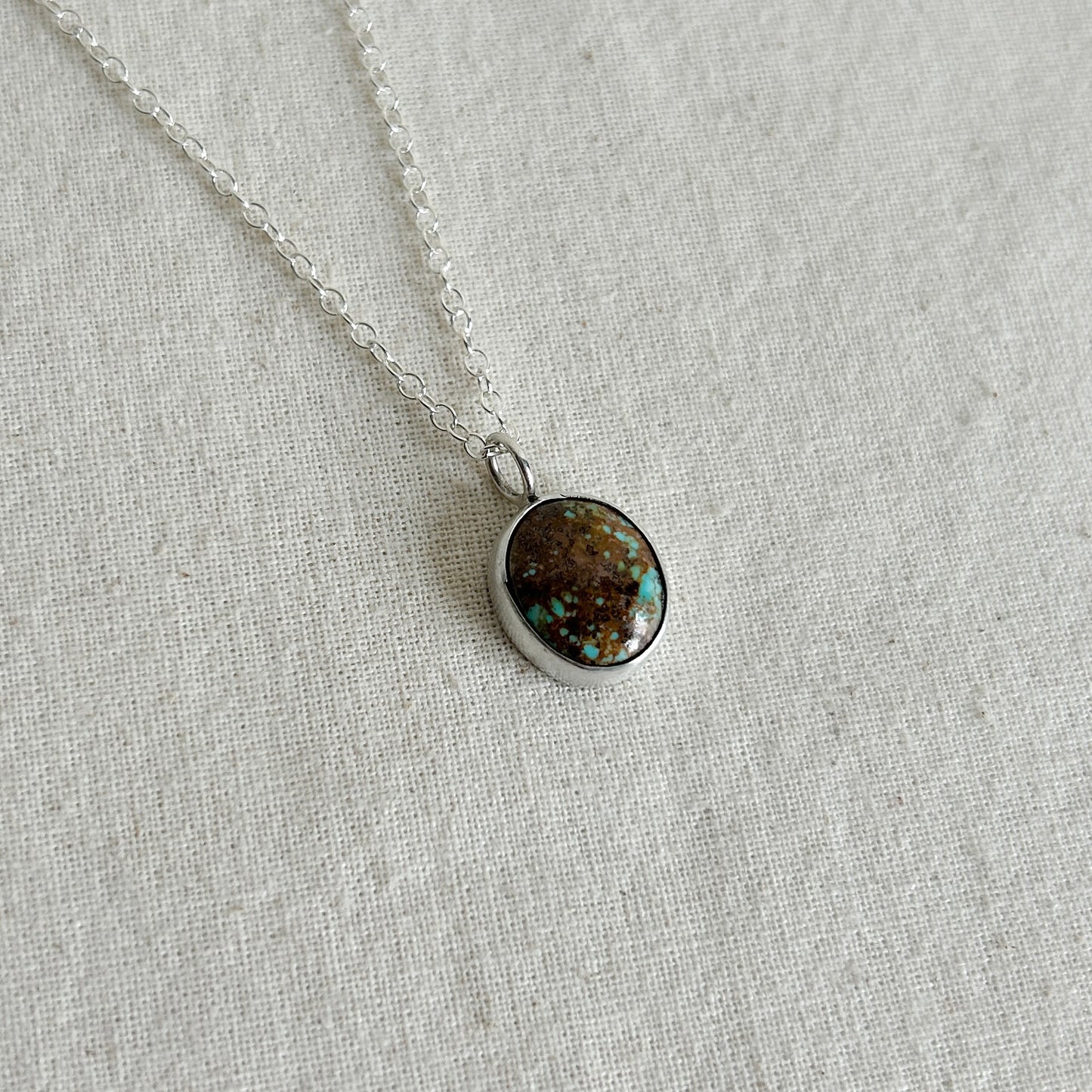 Necklace with a round pendant on a light gray fabric background