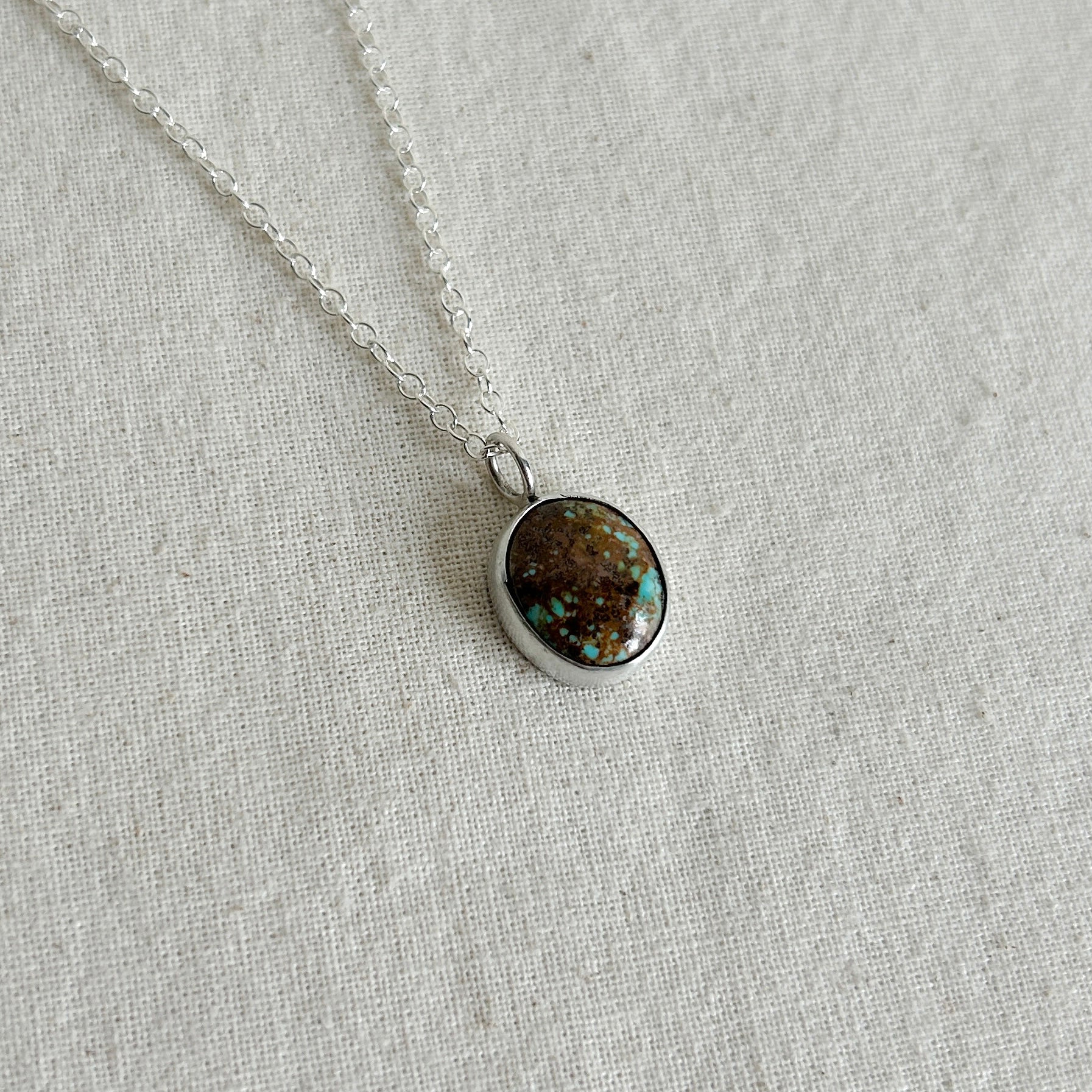 Necklace with a round pendant on a light gray fabric background