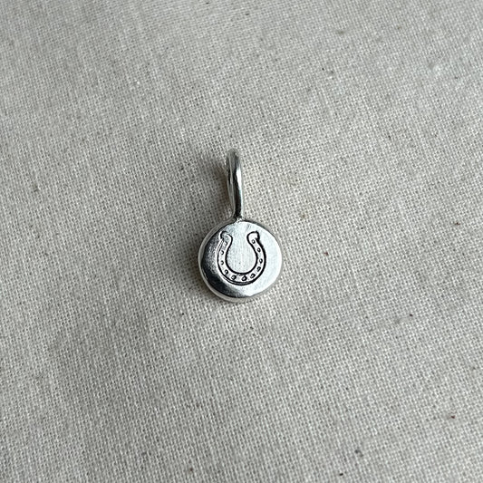 Silver pendant with a horseshoe design on a textured gray background