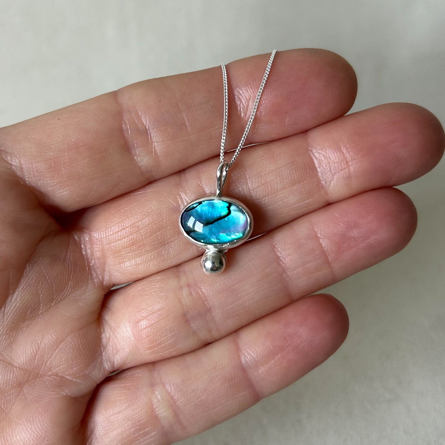 Blue shell necklace on hand of model