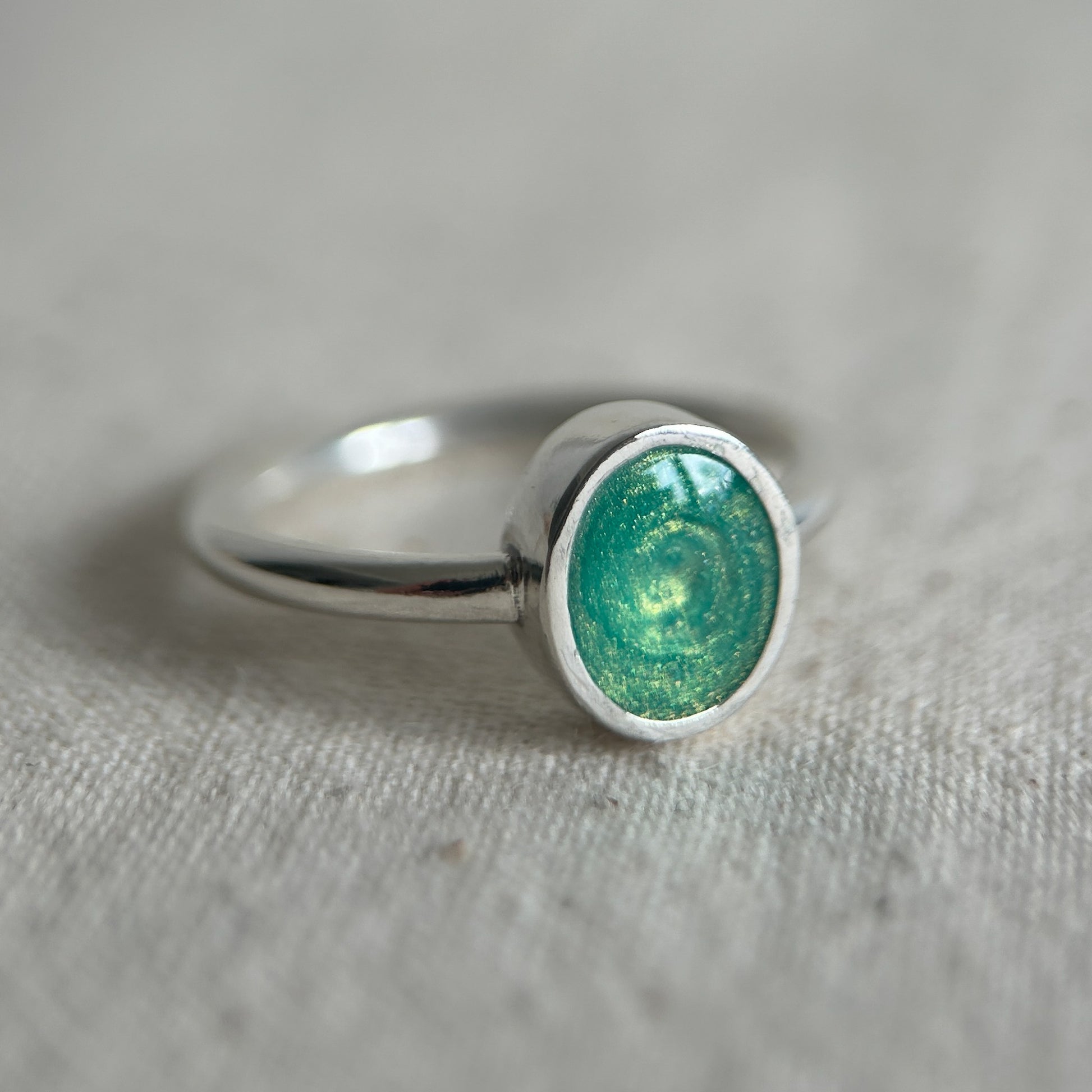 Silver ring with a green stone on a textured gray surface