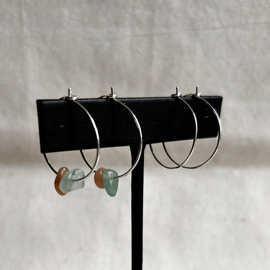 Set of hoop earrings on a black stand against a light gray background