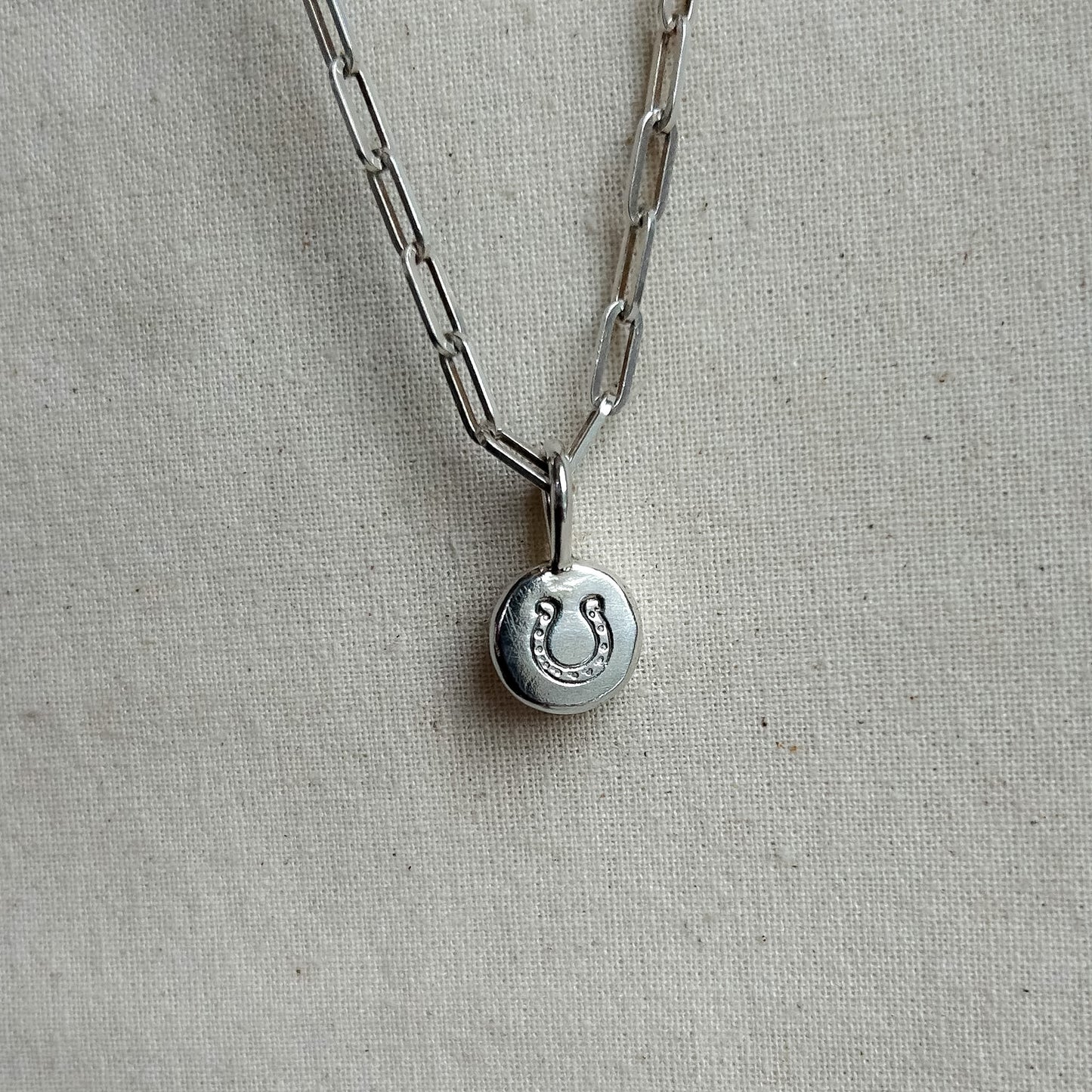 Silver necklace with a round pendant on a light gray background