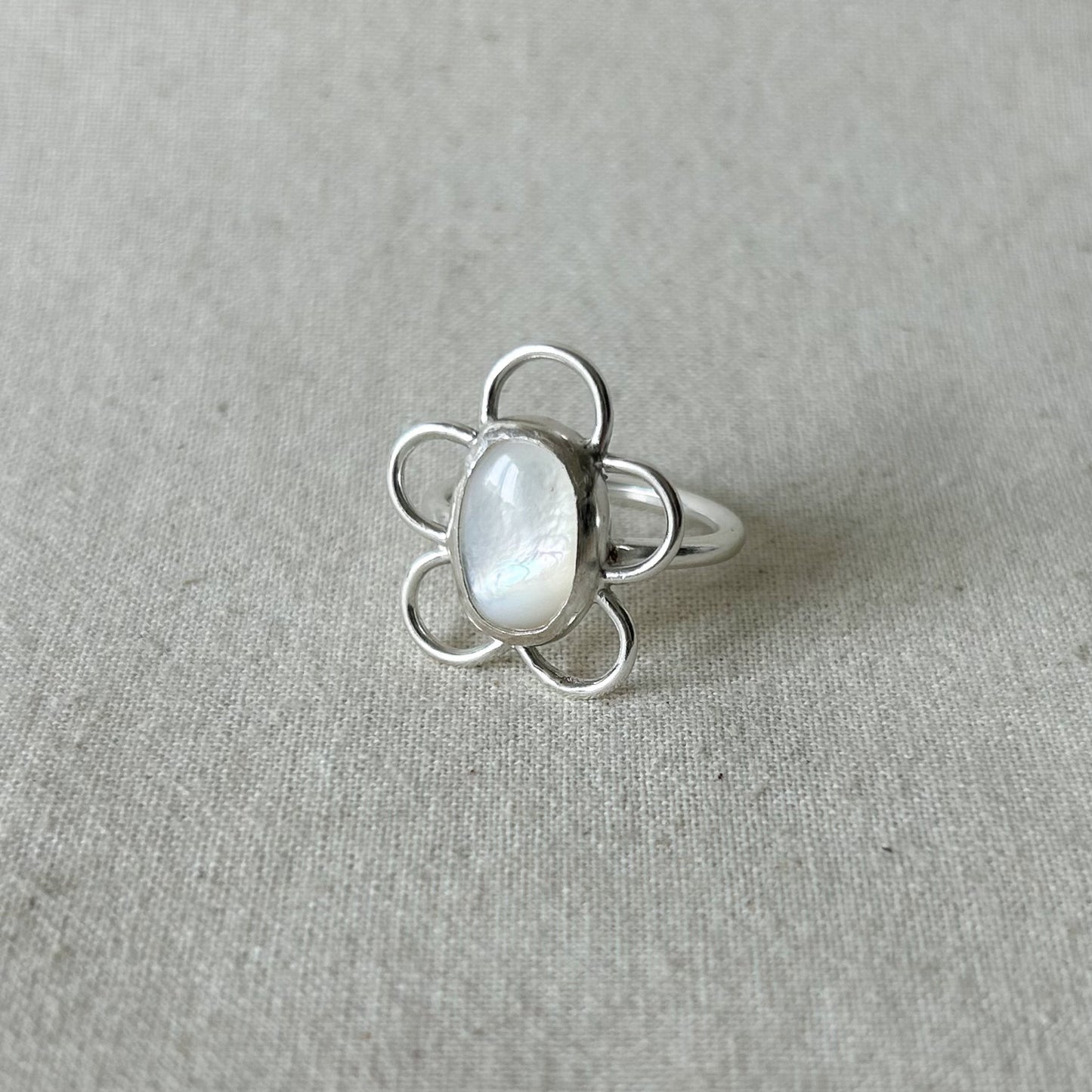 Silver ring with white gemstone on gray background 