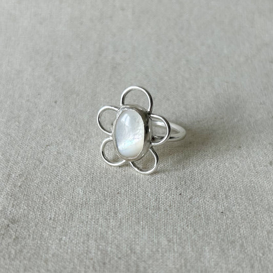 Silver ring with white gemstone on gray background 