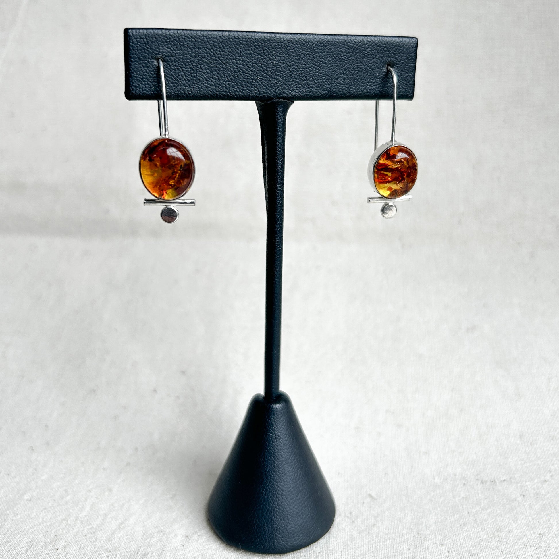 Baltic amber dangle earrings on black leather stand 