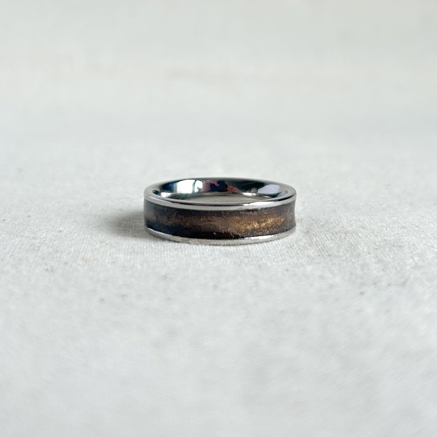 Silver ring with bronze inlay on a grey background