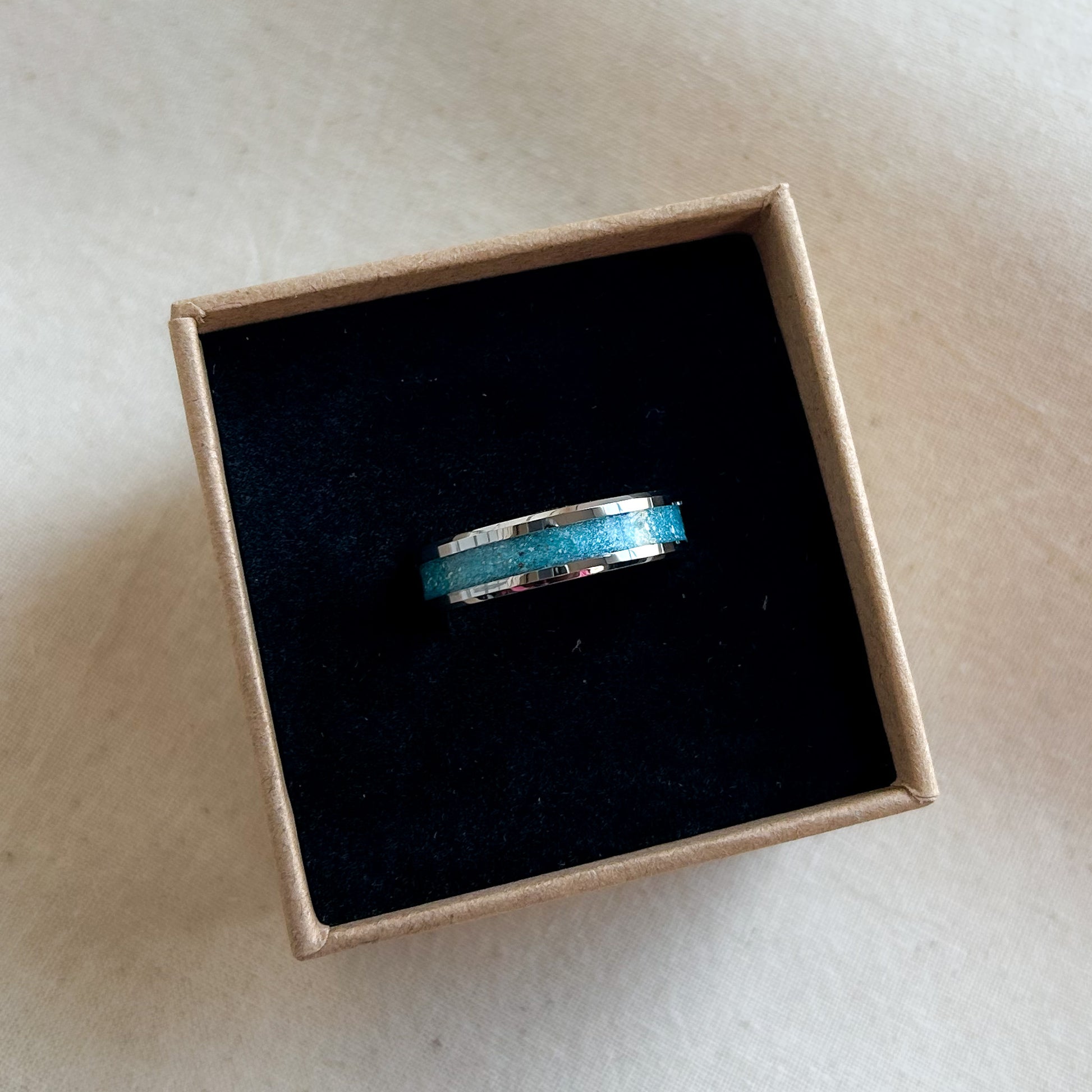 Silver ring with blue centre in a cardboard box on a light background