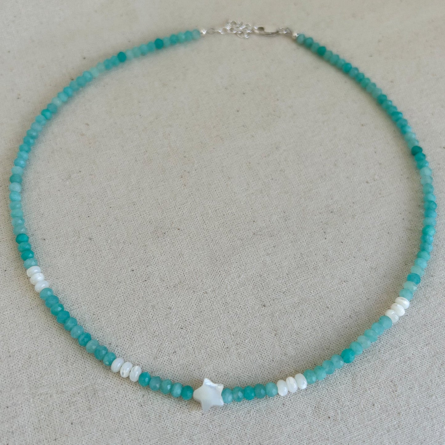 Turquoise beaded necklace with a star-shaped pendant on a light gray background