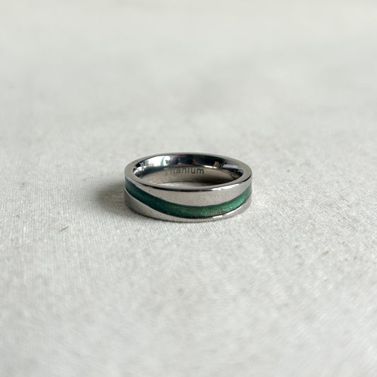 Silver ring with a green inlay on a light gray background