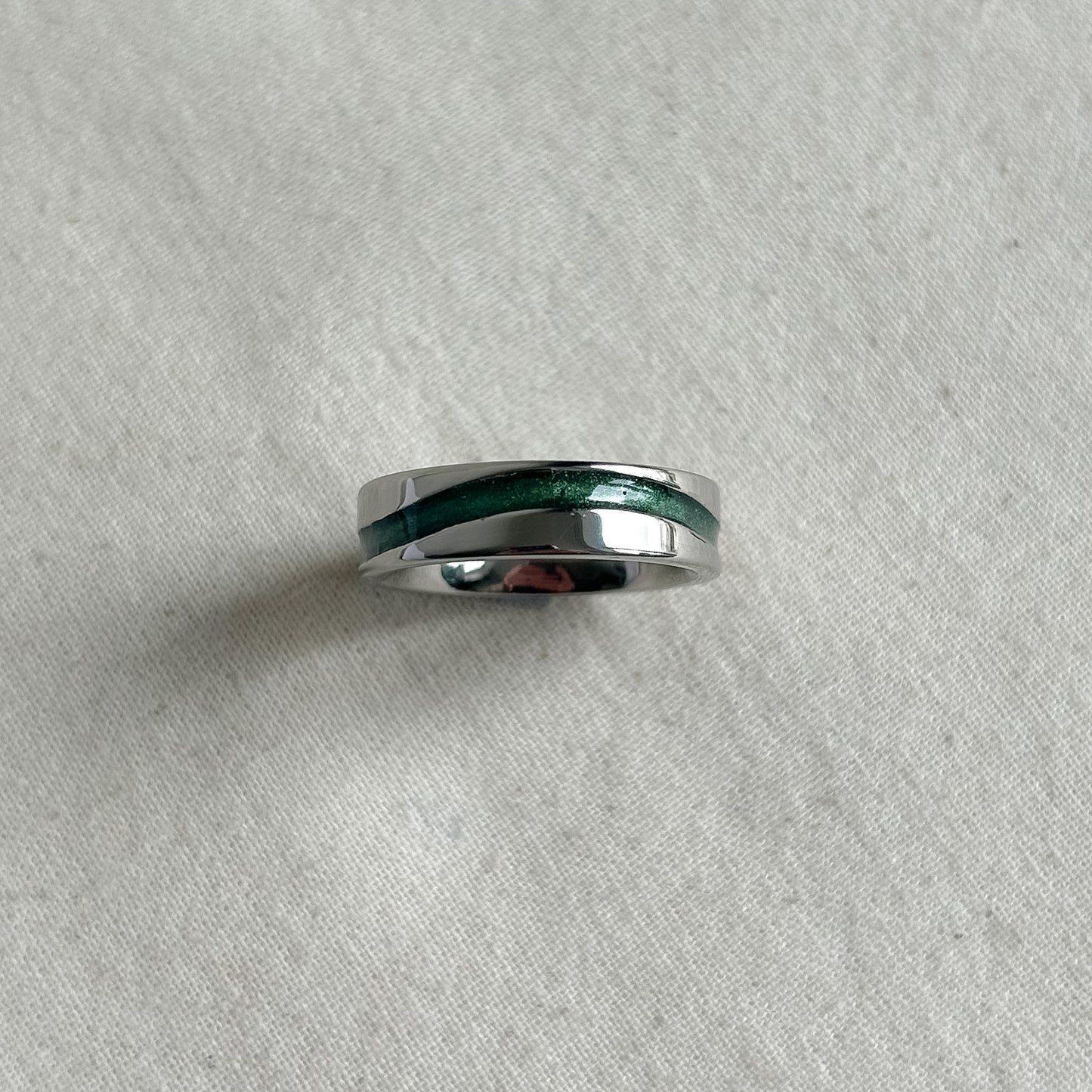 Silver ring with a green inlay on a gray background