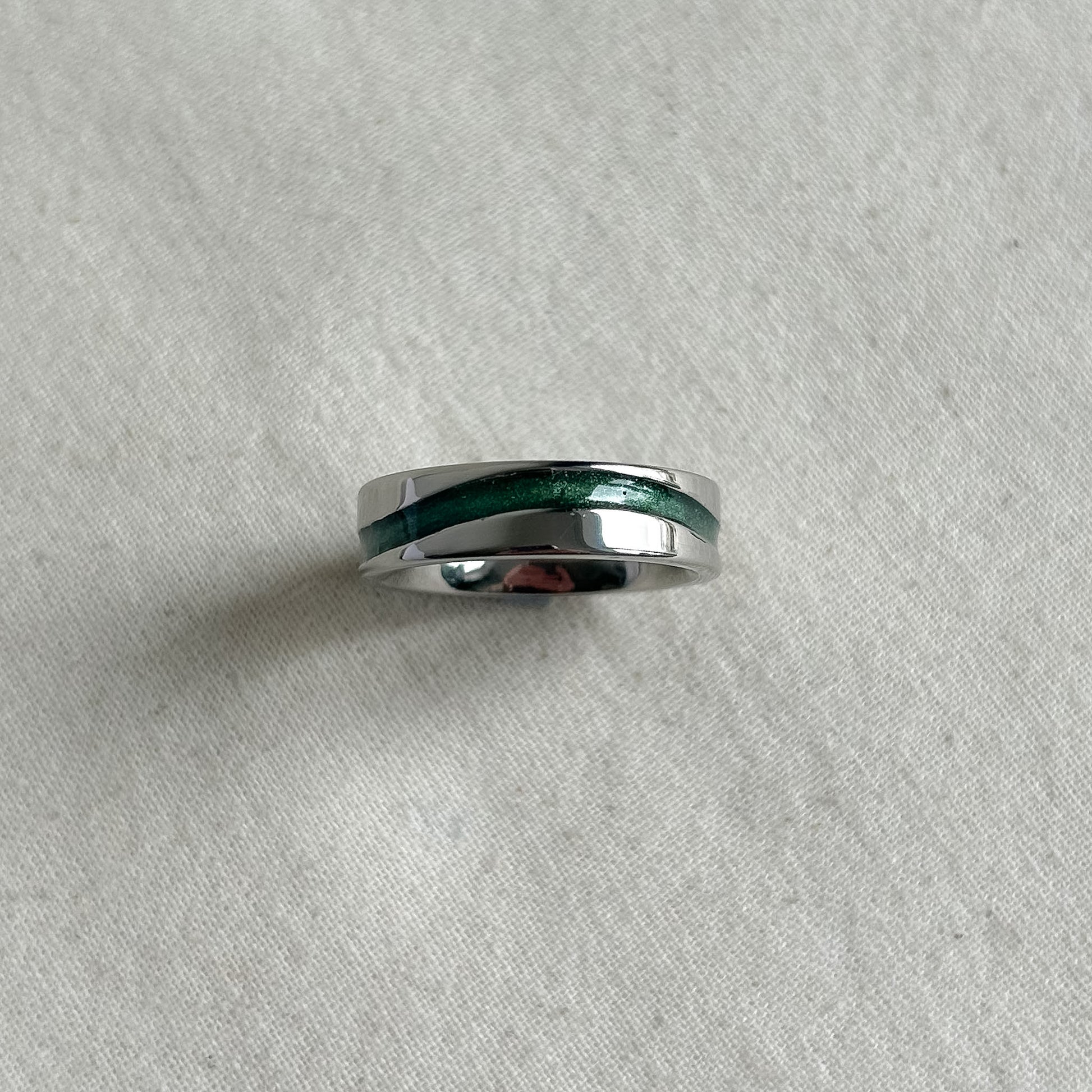 Silver ring with a green inlay on a gray background