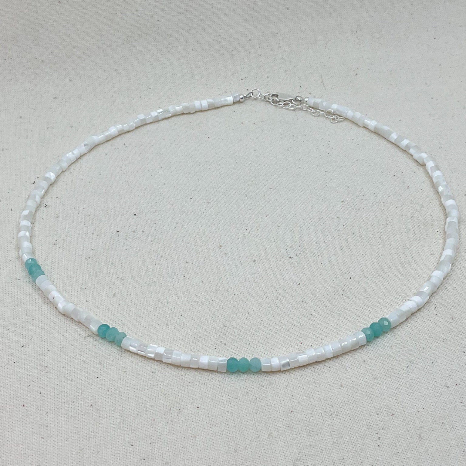 Necklace with white and turquoise beads on a light gray background