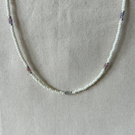 White beaded necklace with pink beads on a gray background 