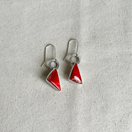 A pair of silver dangle earrings with red Mookaite Jasper stones set in them. 