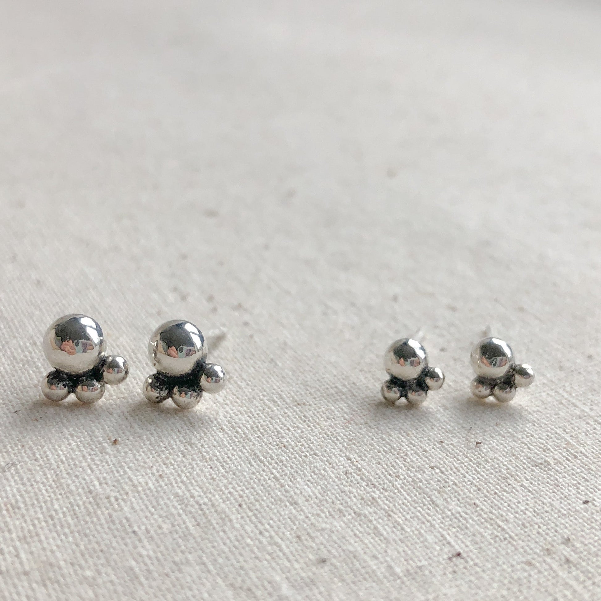 Two pairs of silver studs on a grey background